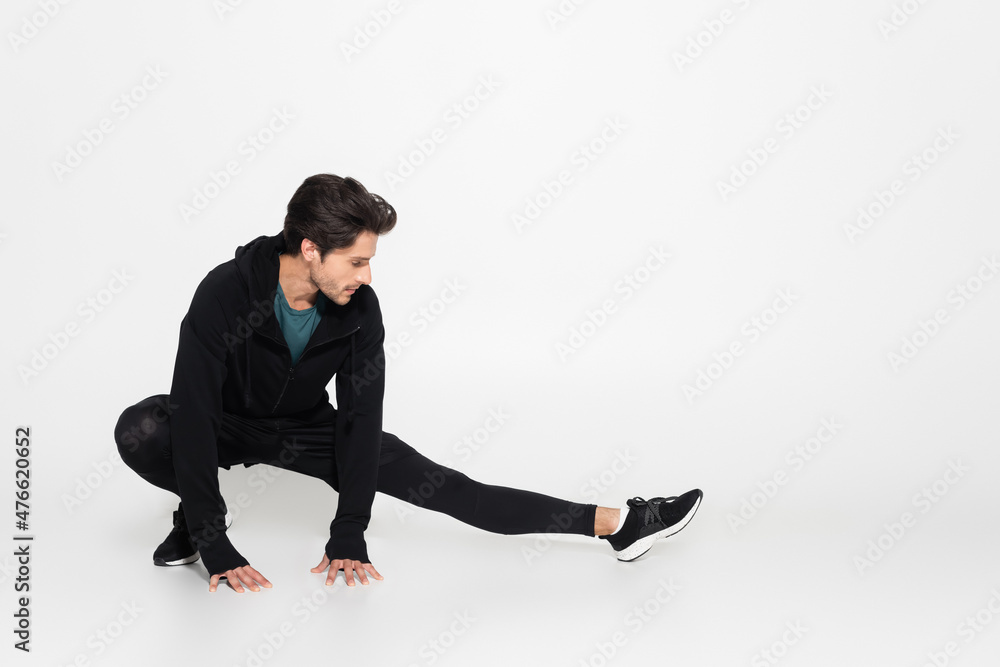 Brunette sportsman stretching on grey background Brunette sportsman stretching on grey background