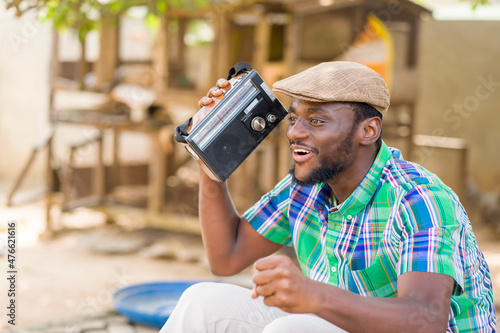 image of excited african man with a music box, black guy holding a wireless radio set- music concept