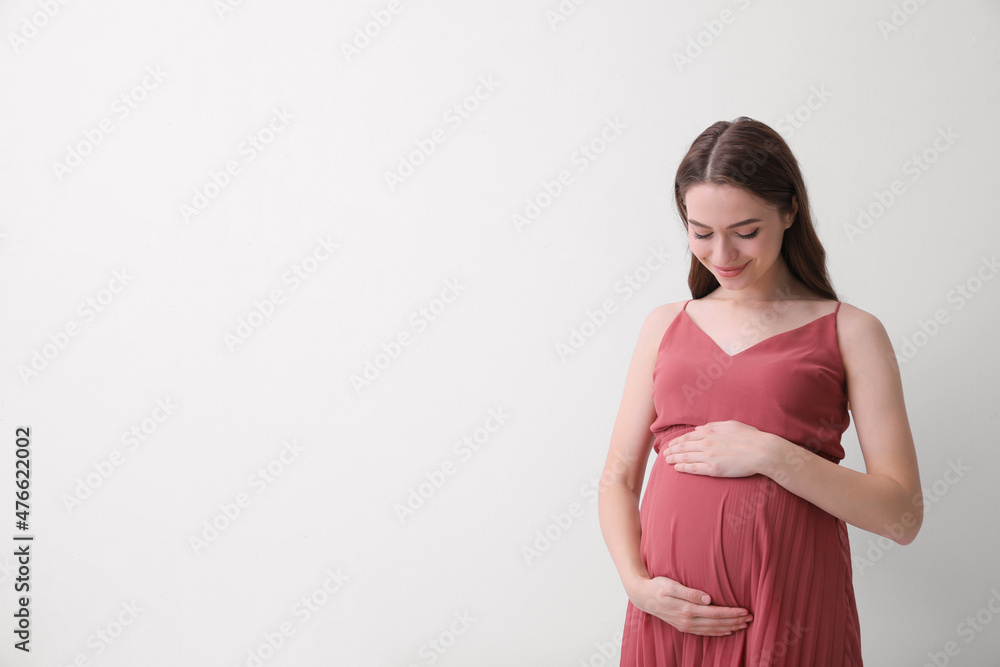 Beautiful young pregnant woman on light background. Space for text Beautiful young pregnant woman on light background. Space for text