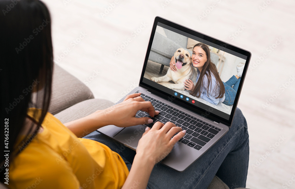 Woman video chatting with female friend online while relaxing on couch Woman video chatting with female friend online while relaxing on couch