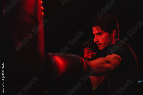 Sportsman in boxing gloves training with punching bag on black background © LIGHTFIELD STUDIOS