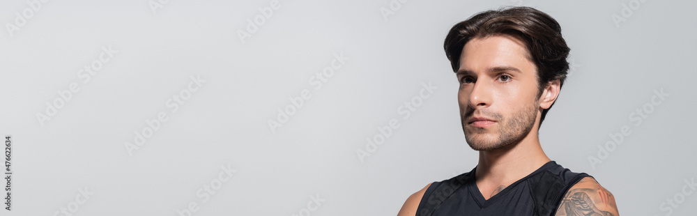 Fototapeta premium Brunette sportsman looking away isolated on grey, banner