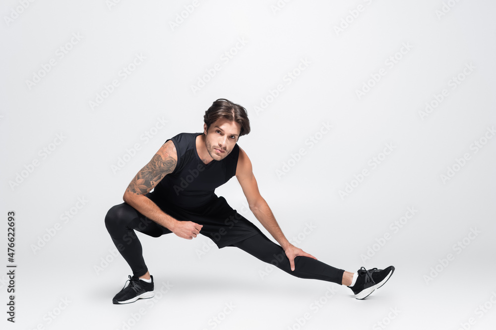 Brunette tattooed sportsman working out on grey background