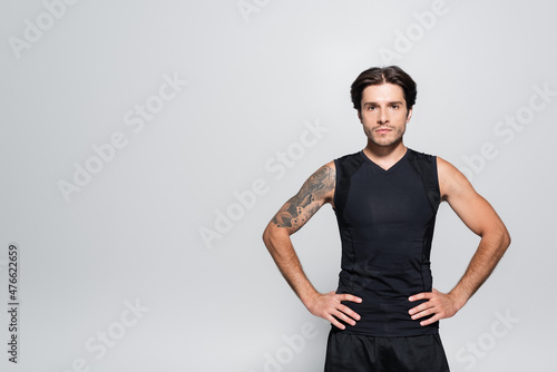 Tattooed sportsman looking at camera isolated on grey