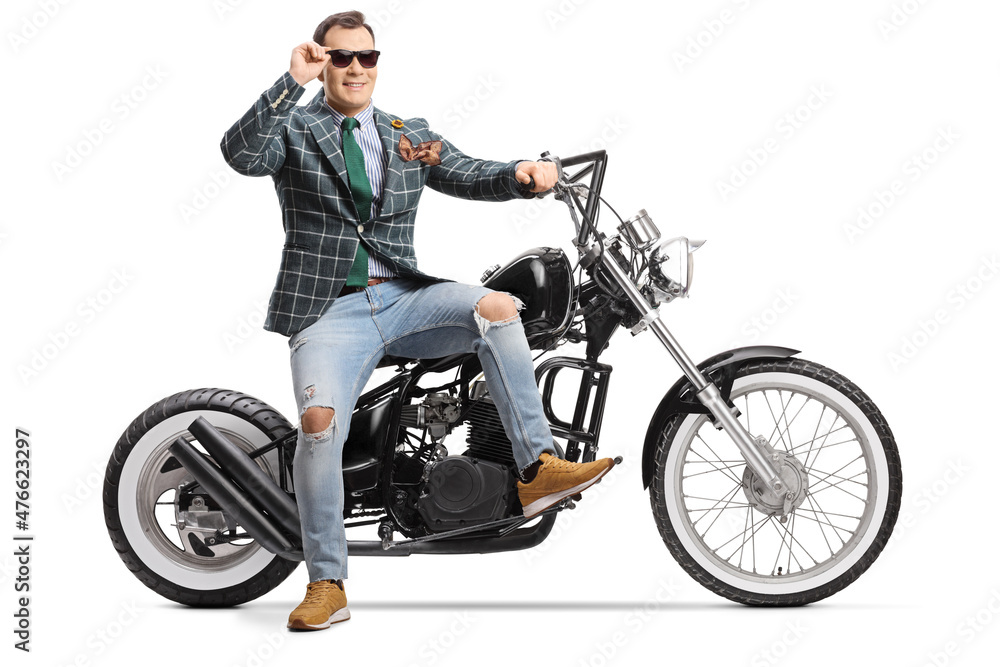Man in stylish suit and jeans sitting on a chopper motorbike and wearing sunglasses