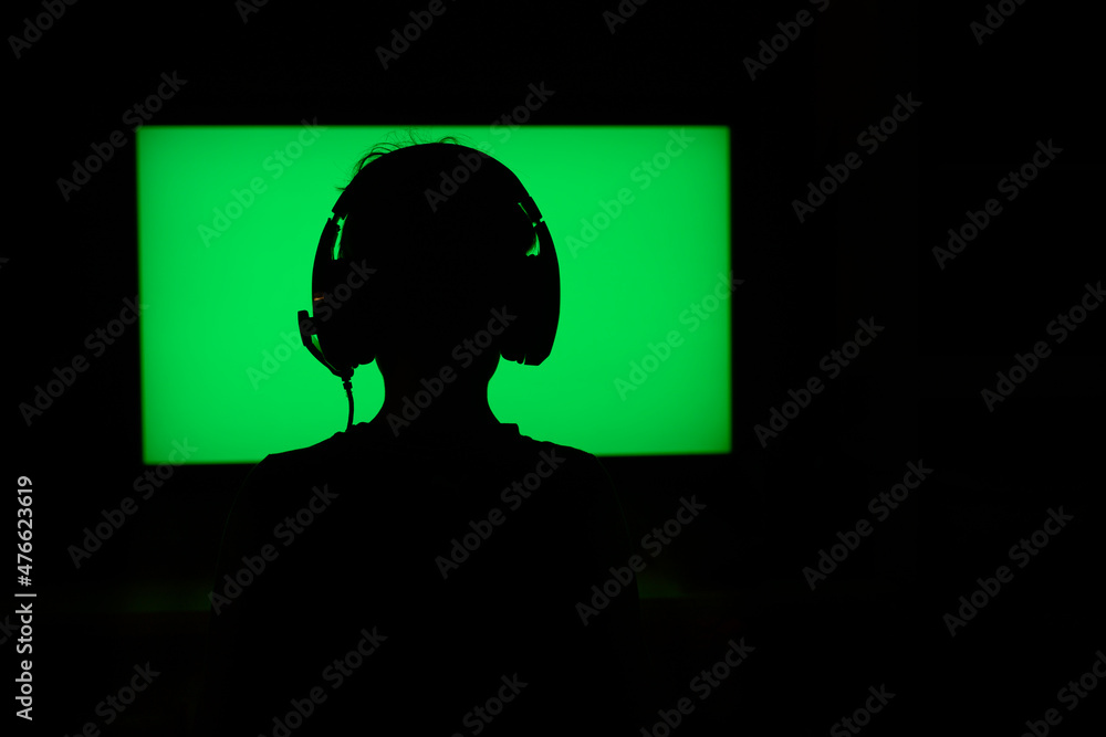 Teen with headphones behind neon green television screen