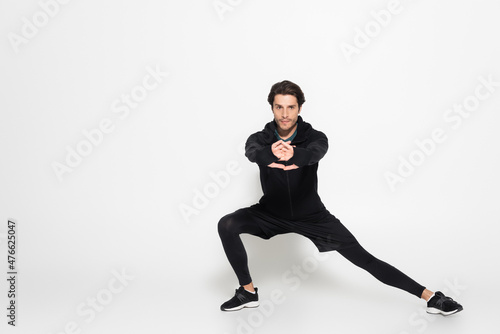 Brunette sportsman looking at camera while training on grey background