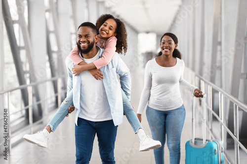 Happy black family traveling with kid, walking in airport
