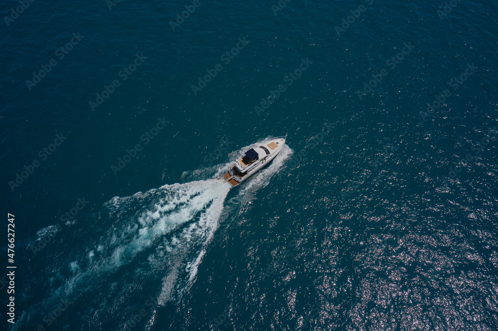 Large white yacht on the water in motion top view. Travel on high-speed  boats on the water. Luxury motor boat on dark blue water aerial view. Yacht  movement on dark water. Stock