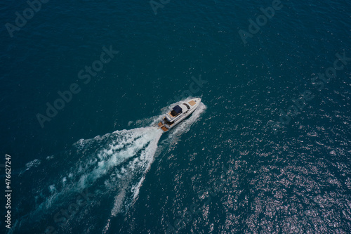 Large white yacht on the water in motion top view. Travel on high-speed boats on the water. Luxury motor boat on dark blue water aerial view. Yacht movement on dark water.