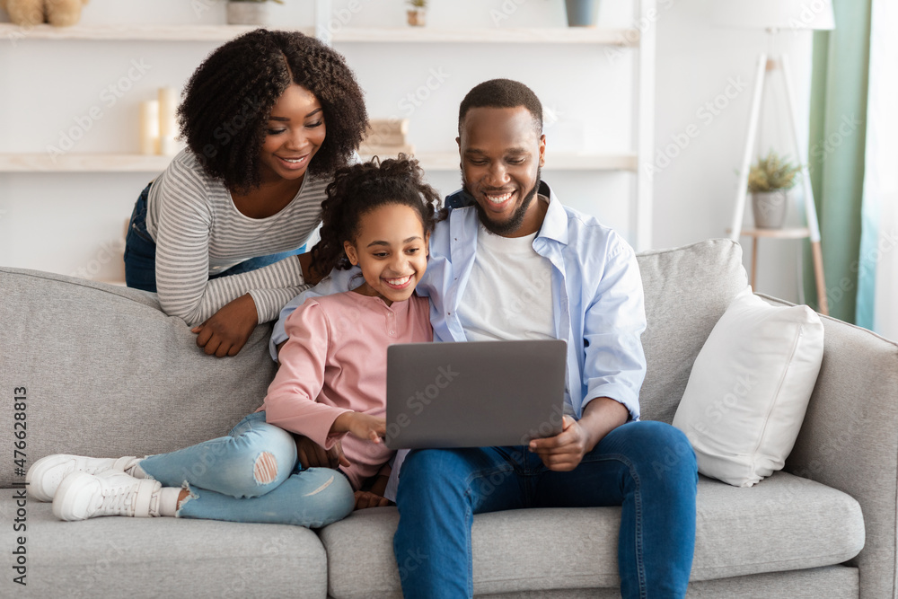 Happy black family using laptop in living room Happy black family using laptop in living room