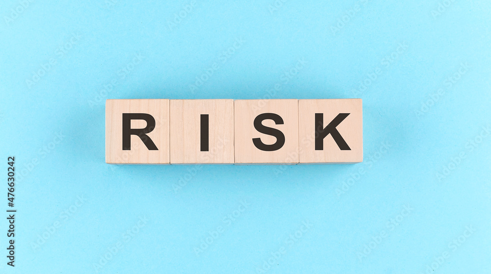 Wooden cube block with text RISK on the blue background Wooden cube block with text RISK on the blue background