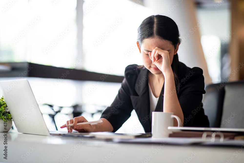 Shot of Asian young businesswoman looking stressed while sitting in her office in front of the laptop. Shot of Asian young businesswoman looking stressed while sitting in her office in front of the laptop.