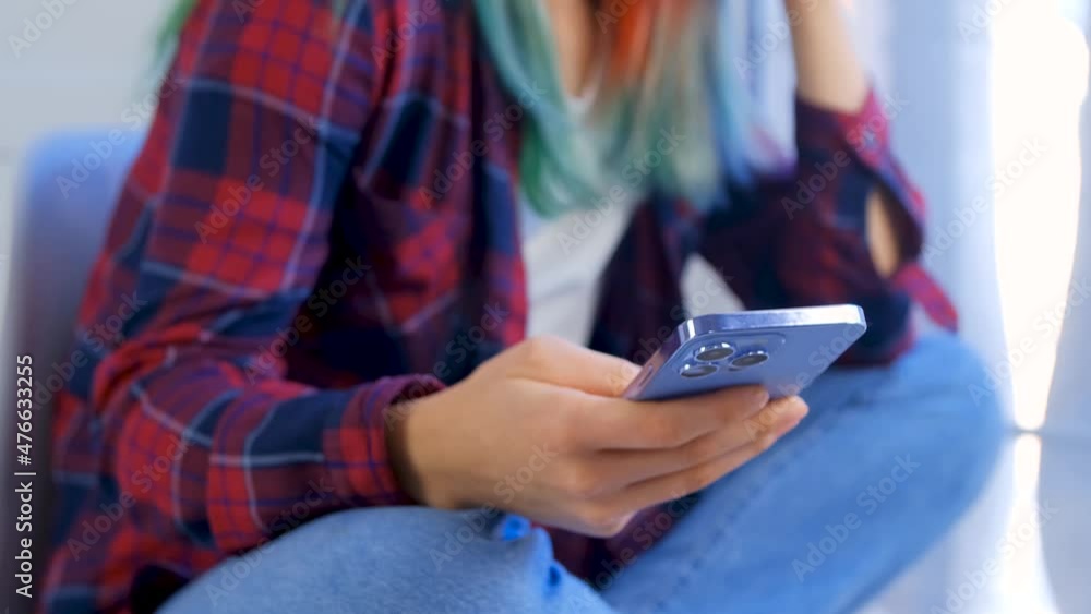 Teen girl using modern mobile phone to browse social media app. Stock video of young woman with dyed hair wearing casual clothing and browsing internet with trendy smartphone Teen girl using modern mobile phone to browse social media app. Stock video of young woman with dyed hair wearing casual clothing and browsing internet with trendy smartphone