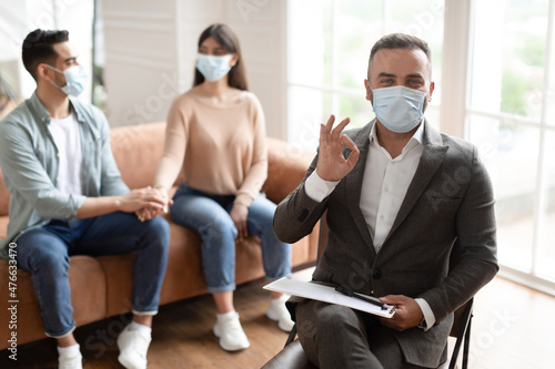 Happy couple reconciling at therapy session, therapists showing thumbs up