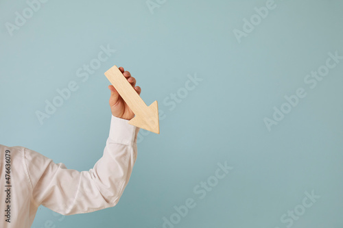 Man holding graph chart arrow that's pointing down on blue blank background with text copyspace Fototapeta