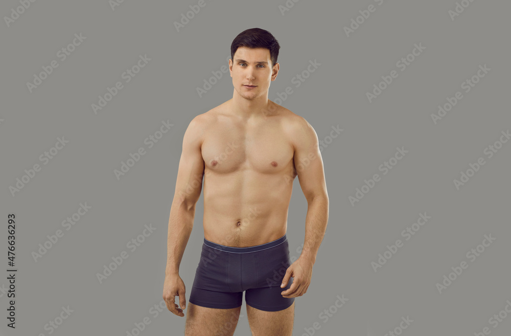 Fototapeta premium Portrait of muscular young Caucasian man in underwear pose on grey studio background advertise clothing. Toned sporty sexy male model in briefs for underclothing wear campaign. Sale, fashion concept.