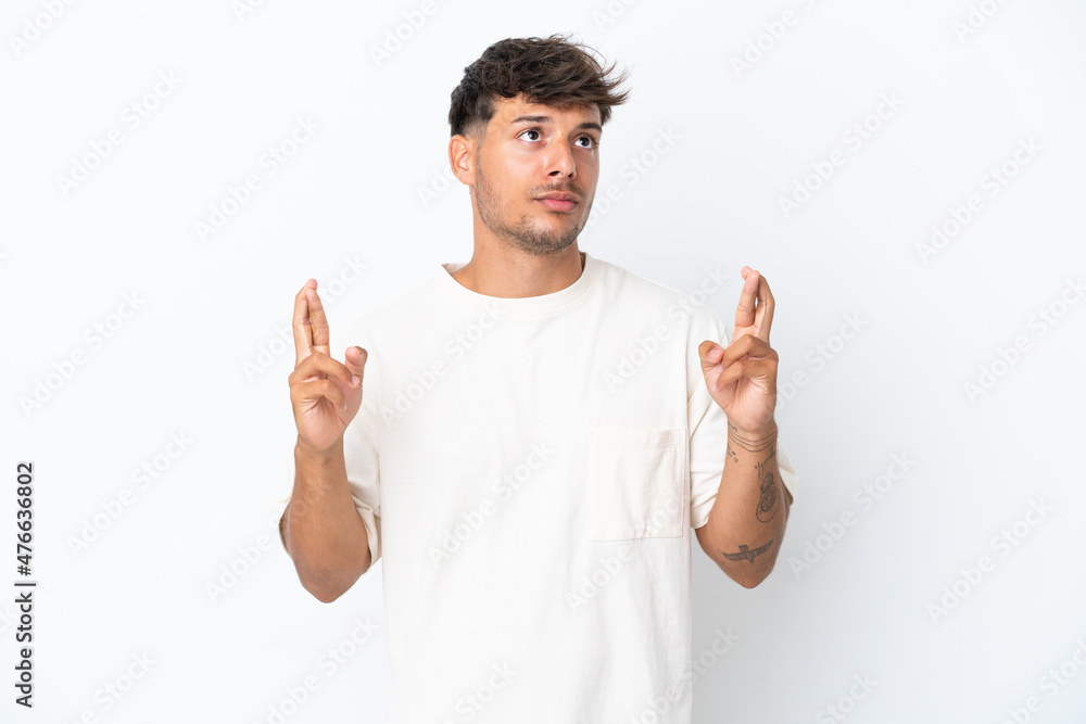 Young caucasian handsome man isolated on white background with fingers crossing and wishing the best Young caucasian handsome man isolated on white background with fingers crossing and wishing the best