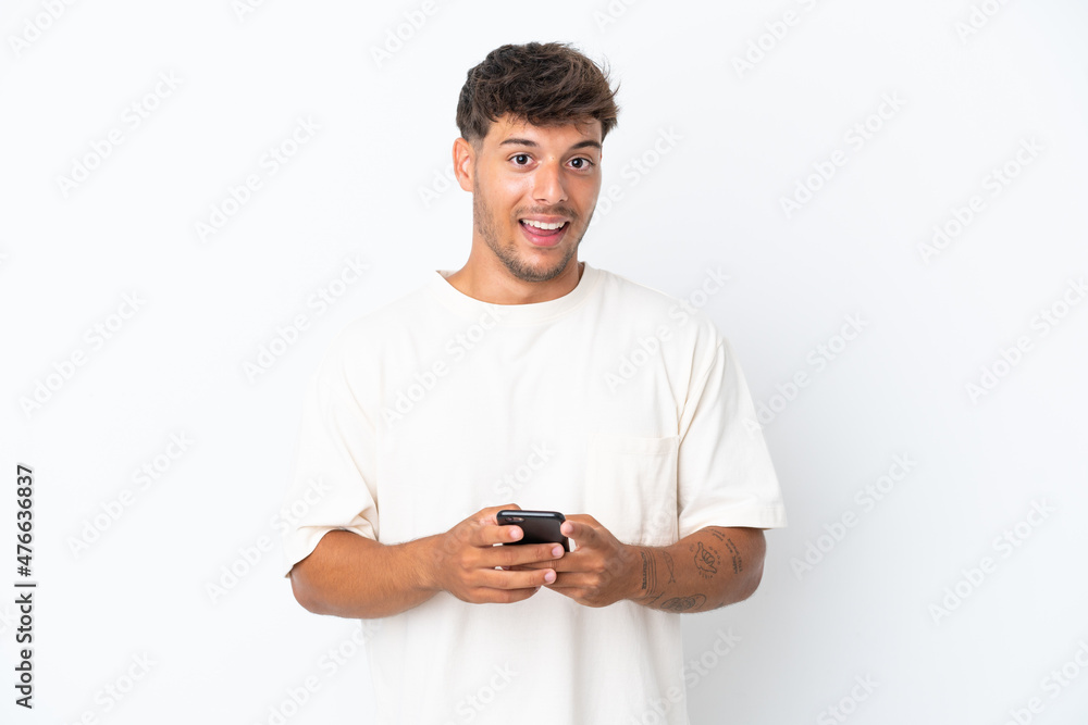 Young caucasian handsome man isolated on white background surprised and sending a message Young caucasian handsome man isolated on white background surprised and sending a message