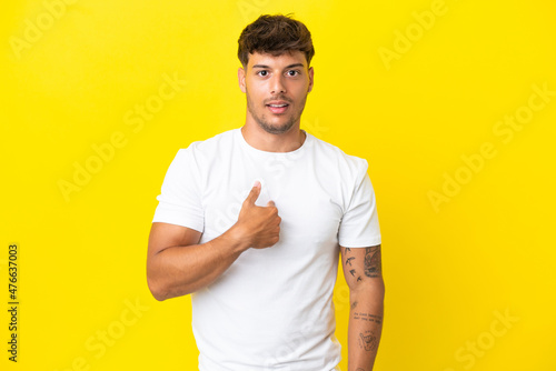 Young caucasian handsome man isolated on yellow background pointing to oneself