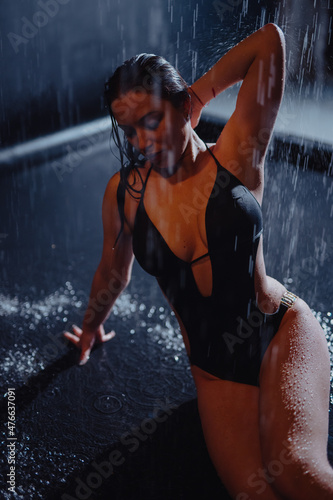 Woman in bikini sitting in aqua studio under rain drops