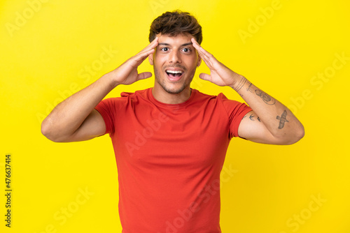 Young caucasian handsome man isolated on yellow background with surprise expression