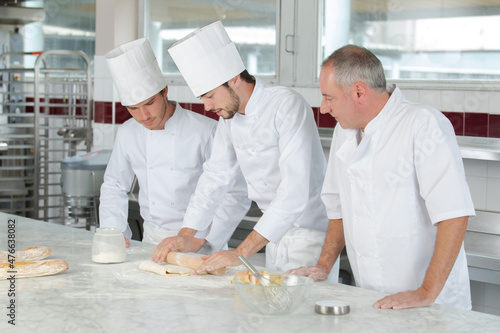 chief chef watching his assistants making a dough