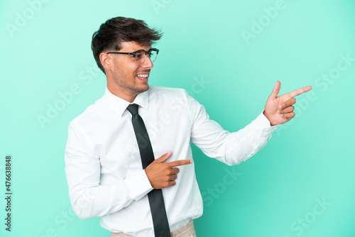 Business caucasian man isolated on blue background pointing finger to the side and presenting a product