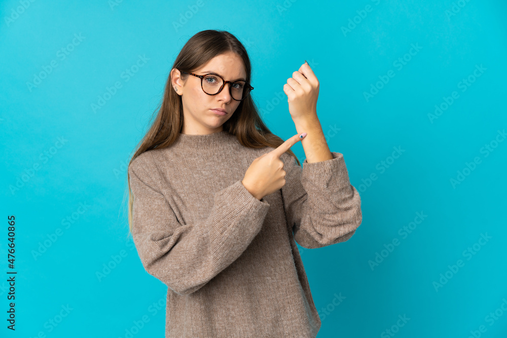 Young Lithuanian woman isolated on blue background making the gesture of being late Young Lithuanian woman isolated on blue background making the gesture of being late