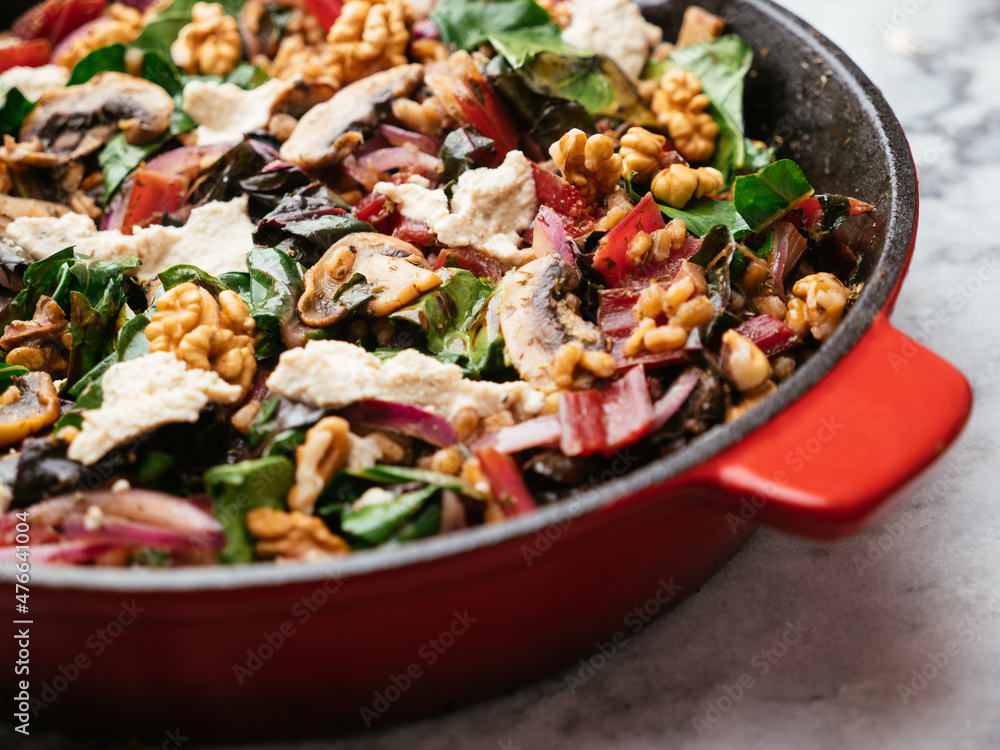 Spelt with red Swiss chard, mushrooms, walnuts and vegan feta in a cast iron pan Spelt with red Swiss chard, mushrooms, walnuts and vegan feta in a cast iron pan