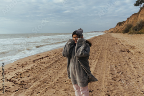 Young woman on cold autumn seashore posing at camera