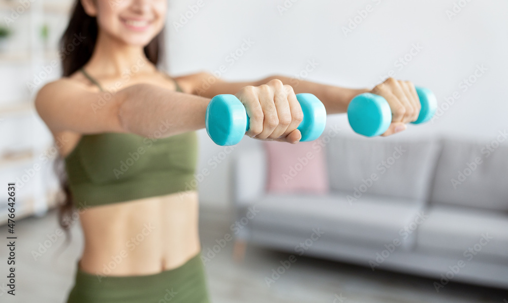 Cropped view of Indian woman doing domestic training, exercising with dumbbells, strengthening her biceps at home Cropped view of Indian woman doing domestic training, exercising with dumbbells, strengthening her biceps at home