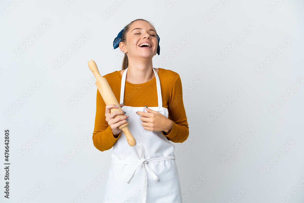 Young Lithuanian woman holding a rolling pin isolated on white background laughing
