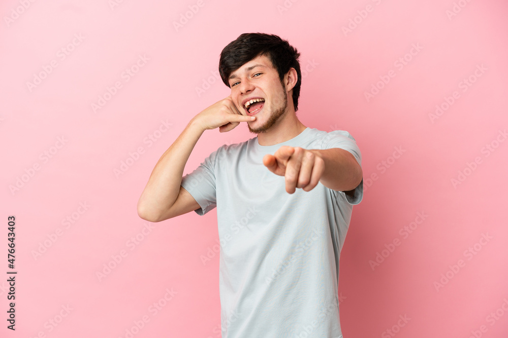 Young Russian man isolated on pink background making phone gesture and pointing front Young Russian man isolated on pink background making phone gesture and pointing front