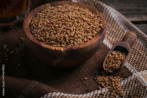 Bowl of fenugreek dry seeds on dark wooden background. Healthy food, Ayurveda and alternative medicine concept