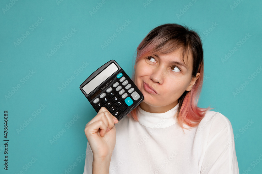 Portrait of a serious female accountant holding a calculator on a blue background. Portrait of a serious female accountant holding a calculator on a blue background.