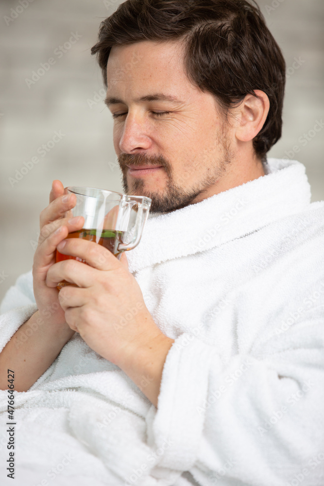 handsome man drinking tea and relaxing in bathrobe handsome man drinking tea and relaxing in bathrobe