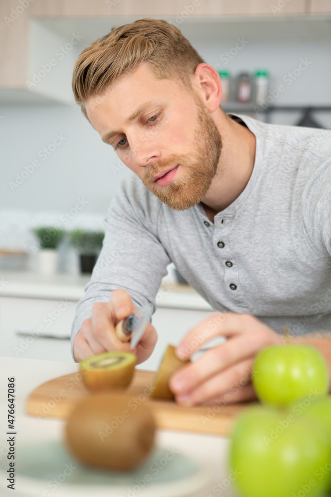 Fototapeta premium man cutting a kiwi fruit in half