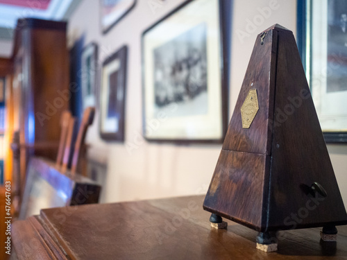 An antique wooden brown metronome on a wall of photographs photo