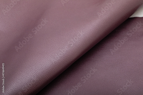 dyed metallic purple glossy folded natural cow leather on the wooden table 