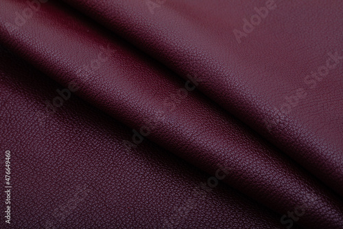 Dark burgundy folded natural premium cow leather on the wooden table 