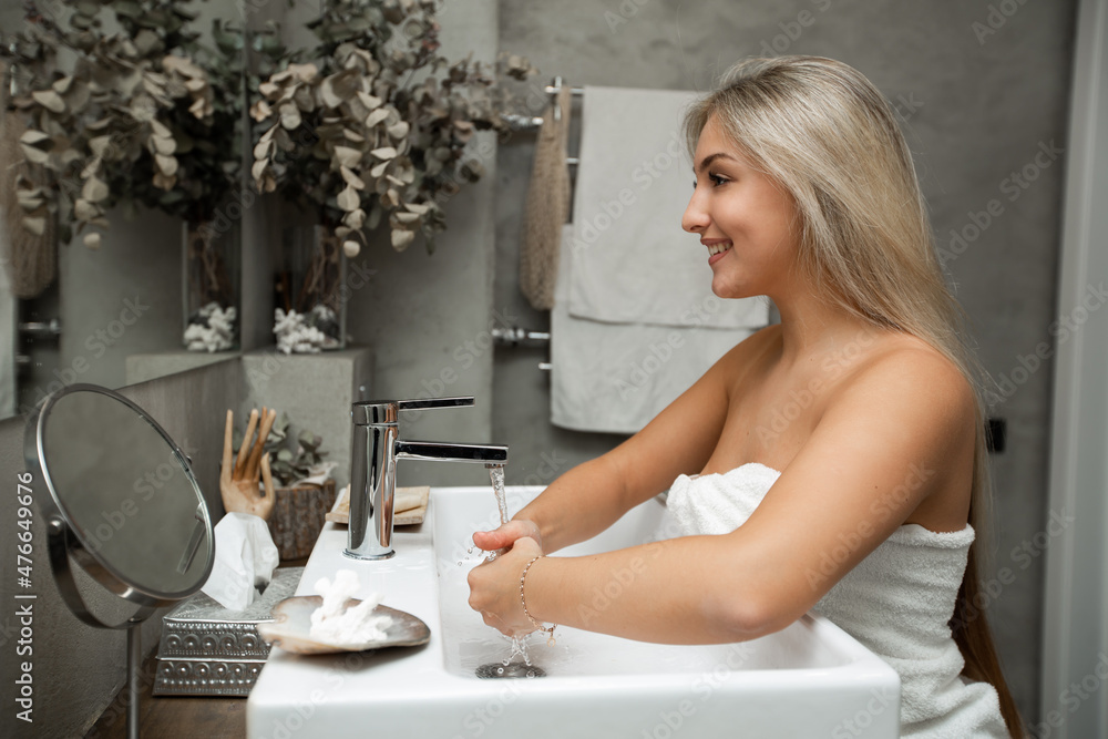 Portrait of a cute caucasian female who washes hands in the bathroom Portrait of a cute caucasian female who washes hands in the bathroom