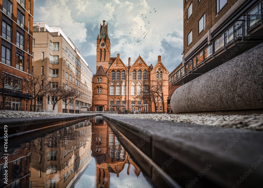 Fototapeta premium Brindley Place red brick church building reflected in water. West Midlands landmark buildings redevelopment in historic city centre reflection in stream. Birds and clouds in sky.
