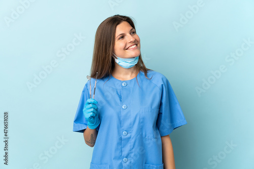 Slovak dentist holding tools isolated on blue background looking side