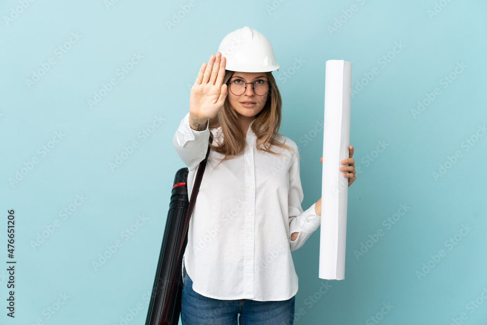 Slovak architect girl holding blueprints isolated on blue background making stop gesture Slovak architect girl holding blueprints isolated on blue background making stop gesture