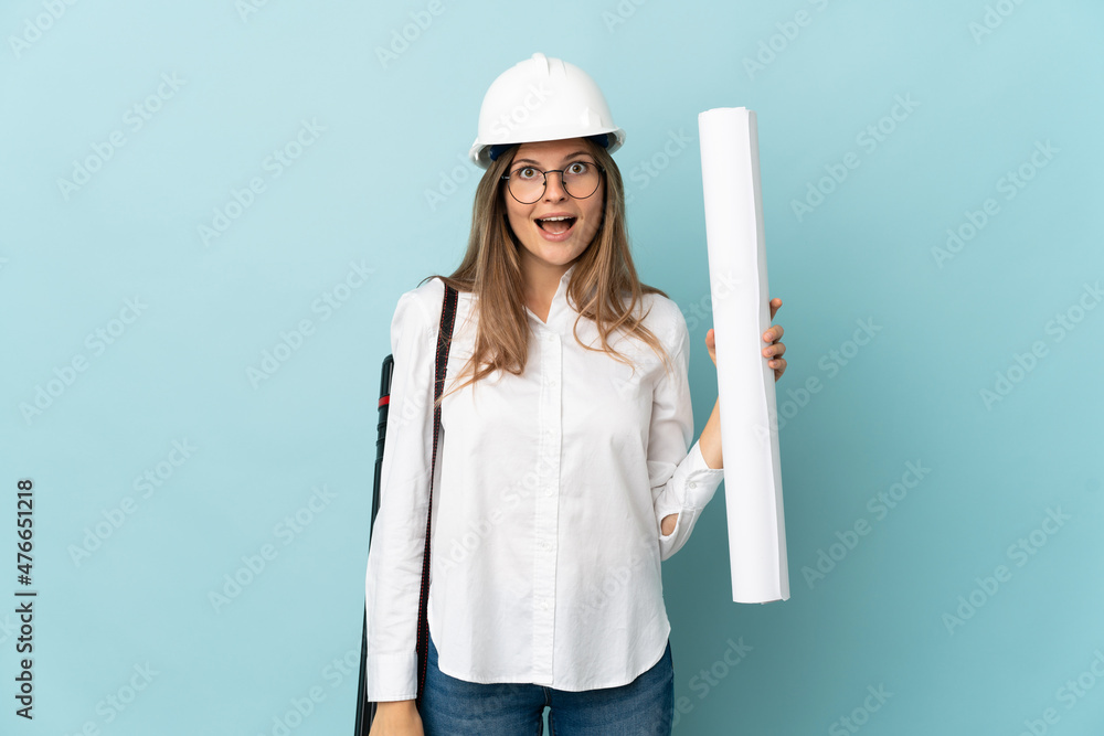 Slovak architect girl holding blueprints isolated on blue background with surprise facial expression Slovak architect girl holding blueprints isolated on blue background with surprise facial expression