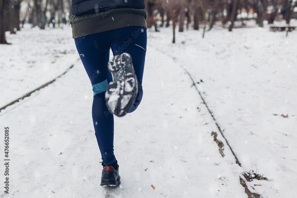 Young woman athlete running in snowy winter park. Close up of sneakers and legs. Active healthy lifestyle Young woman athlete running in snowy winter park. Close up of sneakers and legs. Active healthy lifestyle