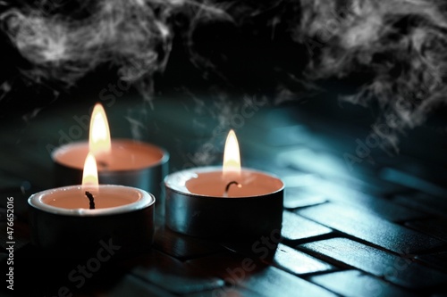 Candles over dark background. Used, almost extinguished. Burned out. Mystical smoke swirls in the dark