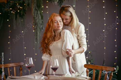 lesbian couple having dinner in a restaurant. One girl hugs her beloved whispering in her ear © toxicoz