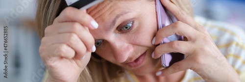 Upset woman in stress holds bank card and talks on phone
